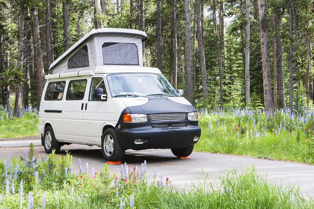 Van converted for camping parked in a paved spot in a campground.
